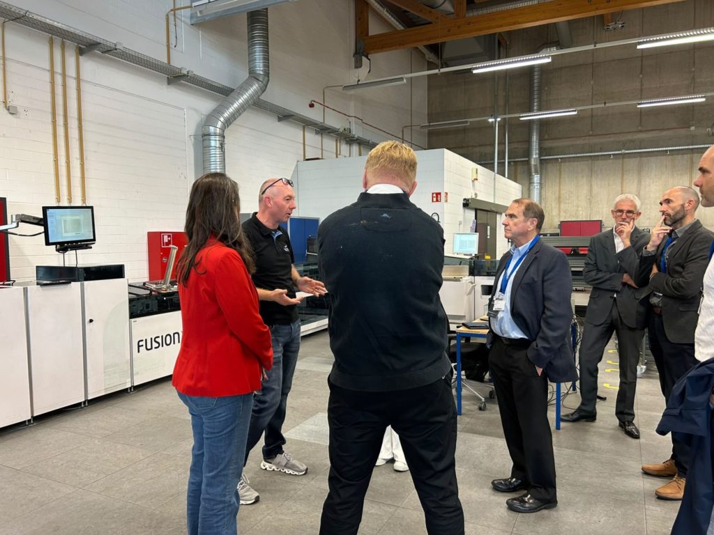 Groupe de personnes écoutant une explication à propos d'une machine de mise sous pli